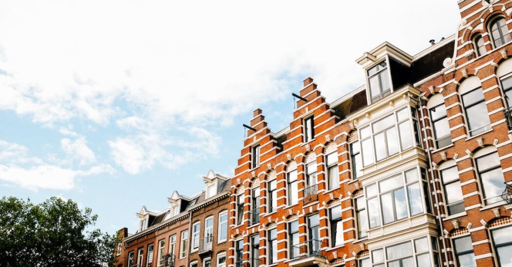 Low angle exterior of contemporary narrow apartment buildings of brown color with white decorative elements in Dutch style