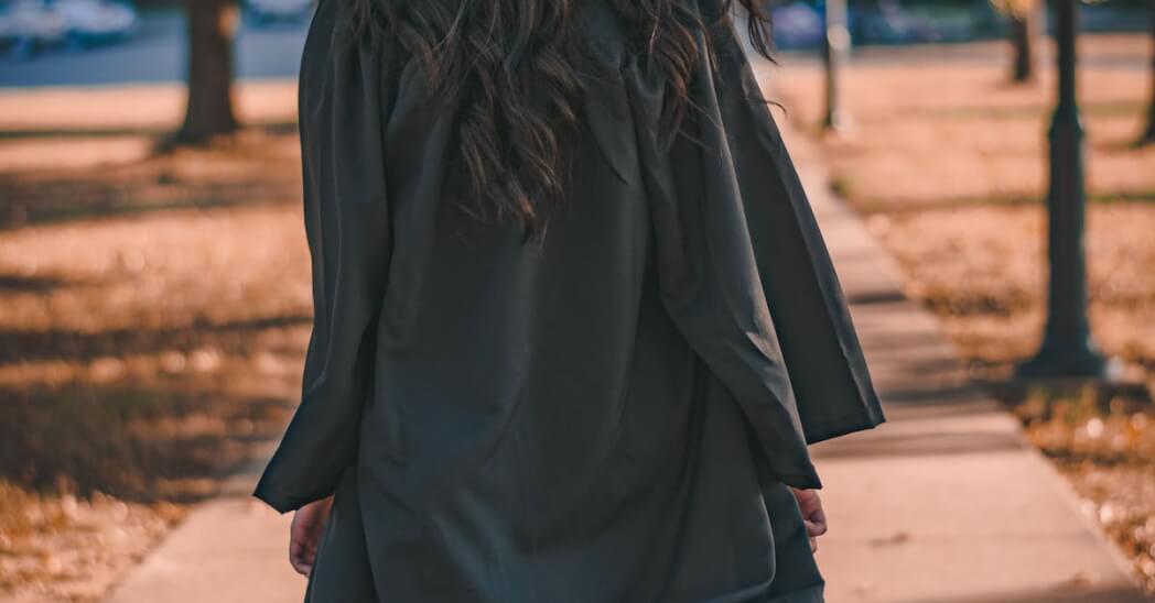 Woman in Black Long Sleeve Dress Standing on Brown Concrete Pathway